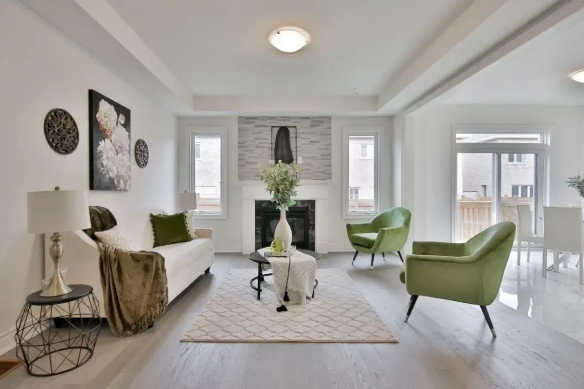 Salon moderne avec canapé blanc, fauteuils verts et une cheminée. La deco de table noir et or ajoute une touche d'élégance.
