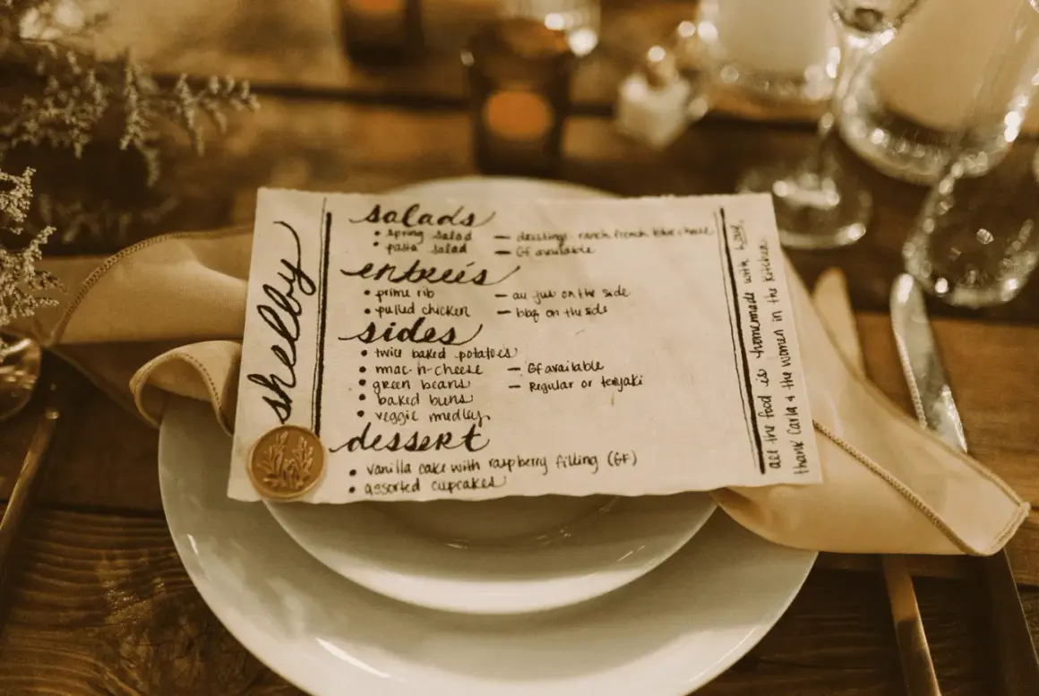 Un menu de mariage manuscrit, joliment présenté sur une assiette, détaille les entrées, accompagnements et desserts.