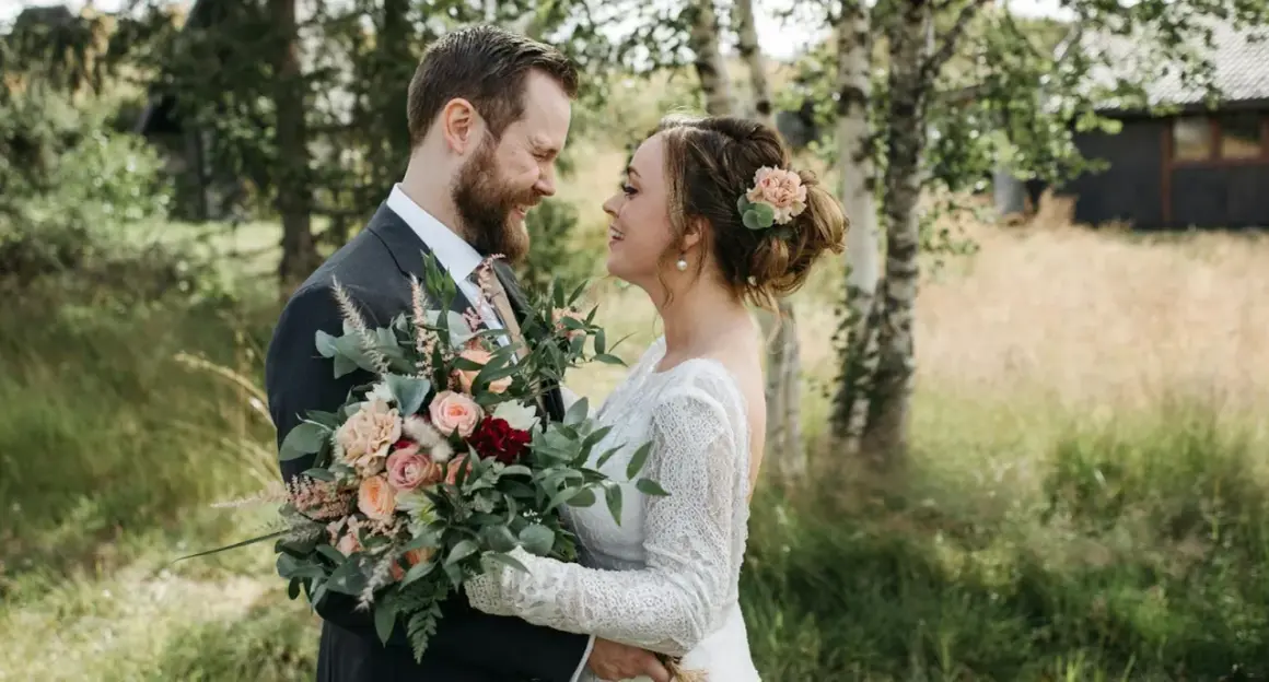 Un couple souriant, bouquet de mariage classique à la main. Idéal pour un texte remerciement mariage classique.