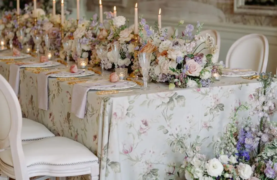 Magnifique table dressée pour un mariage de froment, avec des fleurs pastel, des bougies et une nappe à motifs floraux.