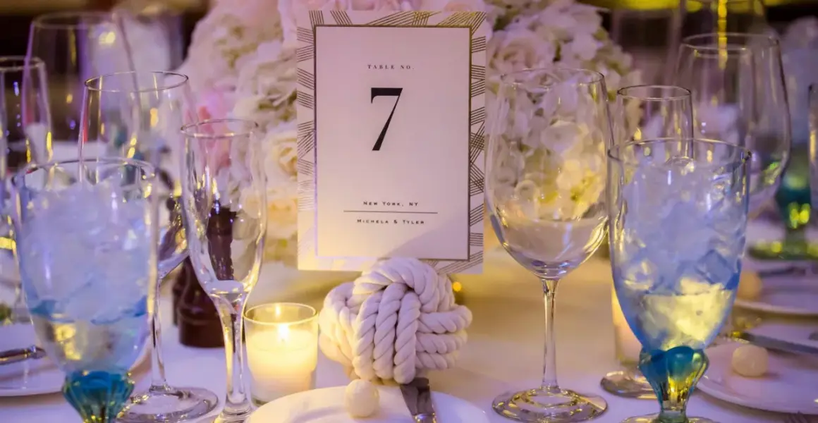 Décoration de table pour un mariage thème marin : numéro de table 7, nœud marin, bougie et verres bleus.