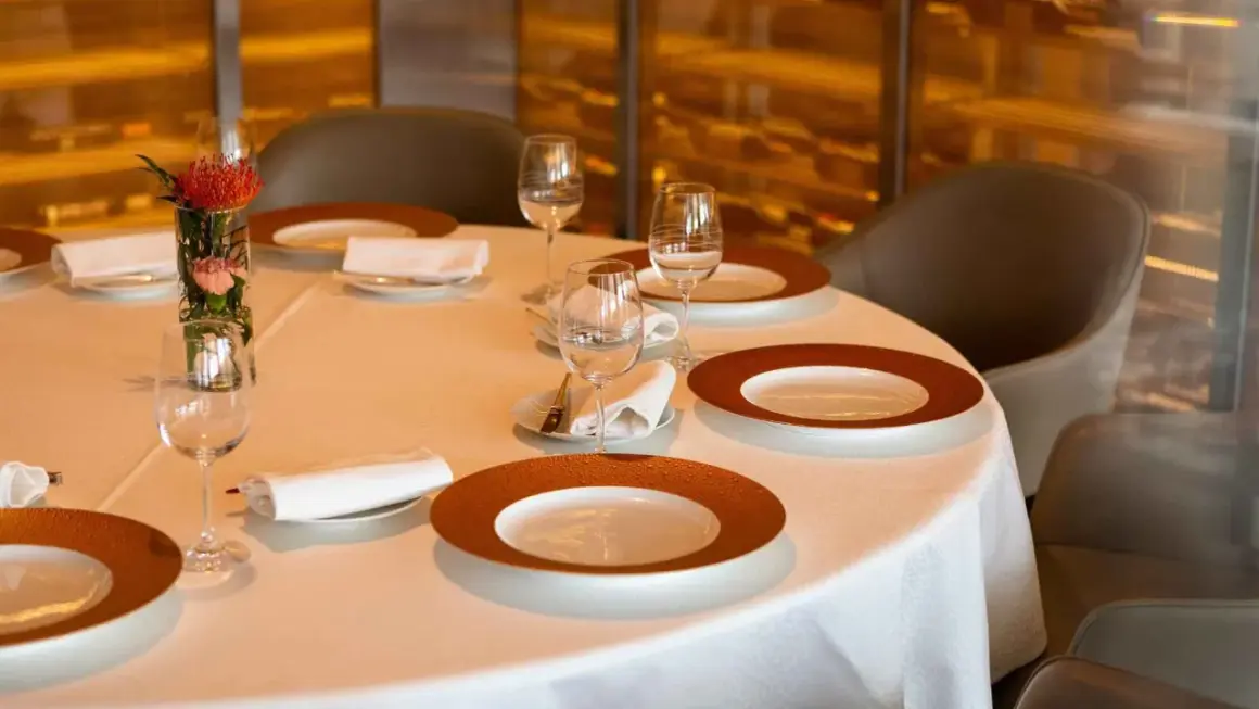 Une table dressée avec élégance, prête pour un repas. Chaque couvert est un pictogramme mettre la table, avec assiettes, verres et serviettes.