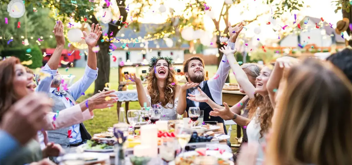 Joyeuse animation anniversaire de mariage en plein air, avec des confettis colorés pleuvant sur des invités souriants et un couple rayonnant.