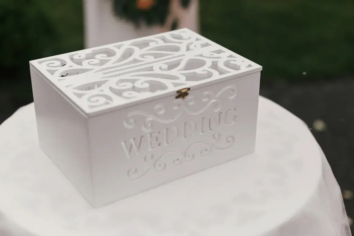 Boîte blanche décorée pour les vœux de mariage, ornée du mot "WEDDING". Une urne élégante pour recueillir les messages des invités.