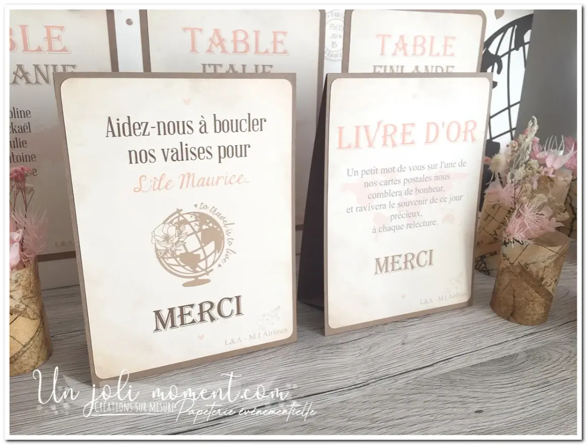 Un **livre** d'or et une carte "Aidez-nous à boucler nos valises pour l'Île Maurice" sur une table en bois, décorés de fleurs séchées.