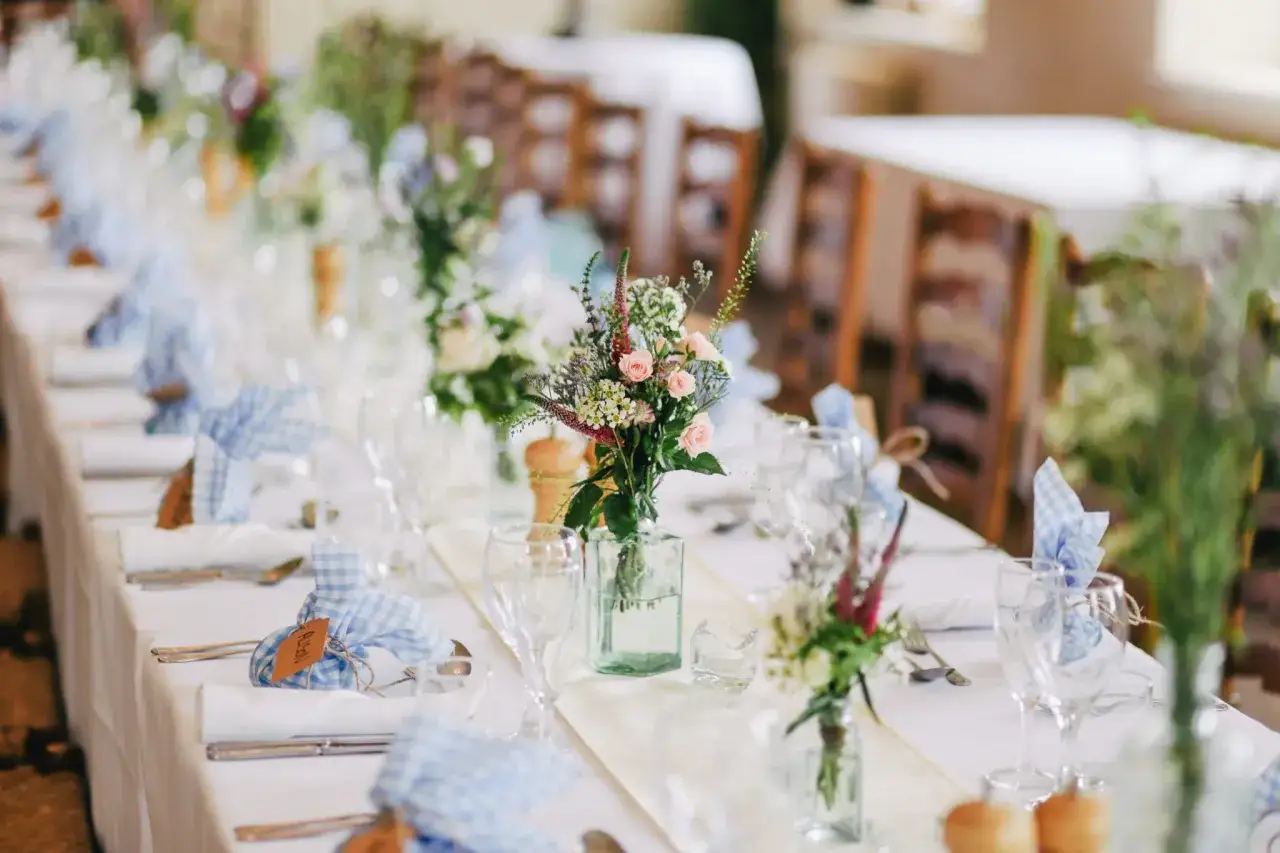D&eacute;coration de mariage champ&ecirc;tre avec des bouquets de fleurs d&eacute;licates et des serviettes &agrave; carreaux bleus.