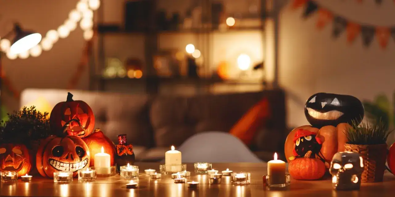 Ambiance d'Halloween avec une deco table fait maison : citrouilles sculptées, bougies vacillantes et guirlandes lumineuses créent une atmosphère effrayante et chaleureuse.