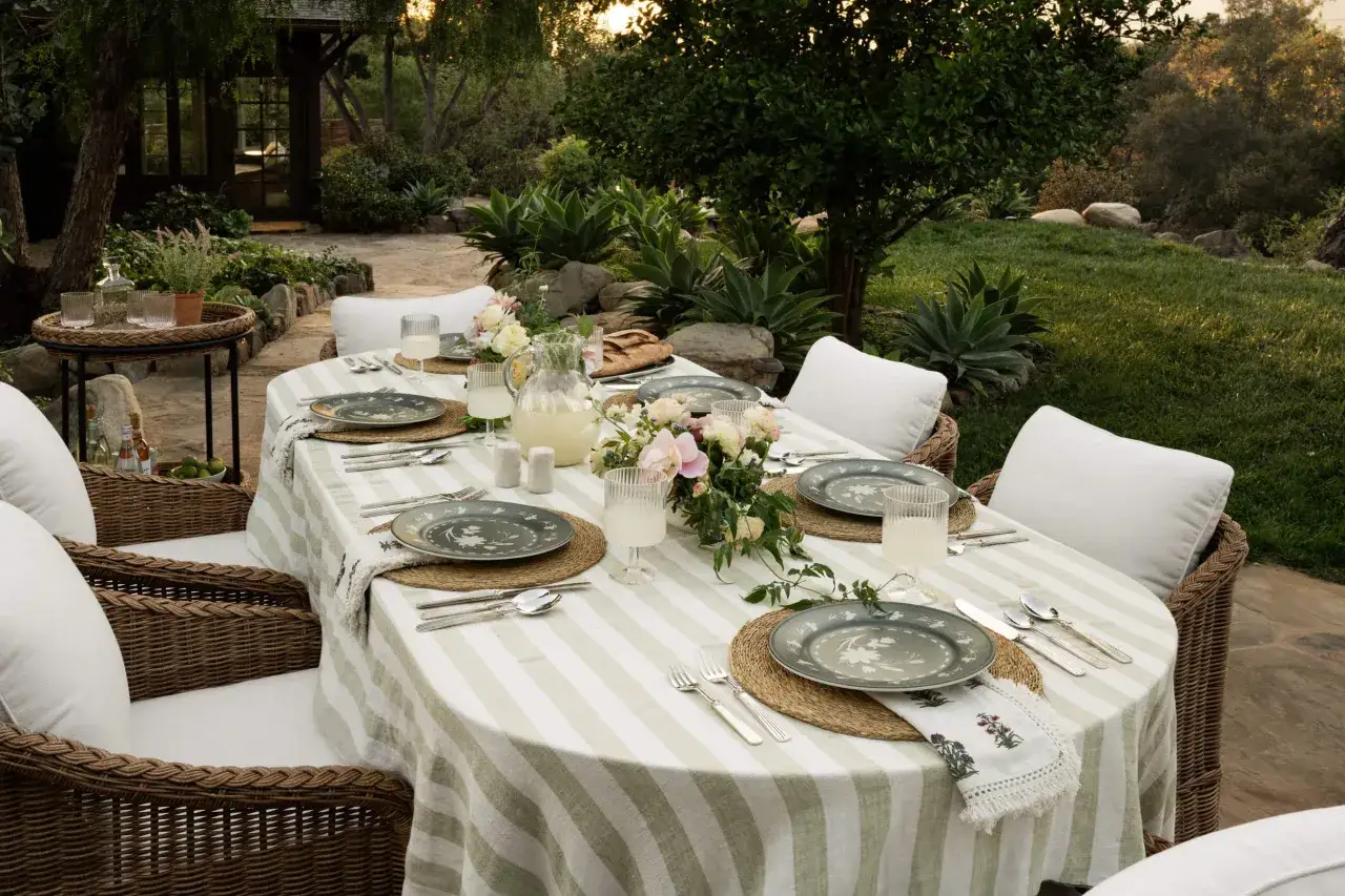 Une belle table est pr&ecirc;te &agrave; &ecirc;tre mise en ext&eacute;rieur, avec des assiettes fleuries, des verres remplis de limonade et un bouquet de fleurs fra&icirc;ches.