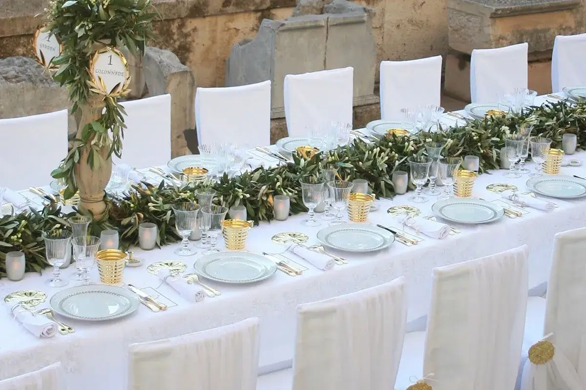 Table dressée pour une fête, avec des guirlandes d'olivier et des bougies. Un texte de remerciement noces d'or pourrait accompagner cette belle table.