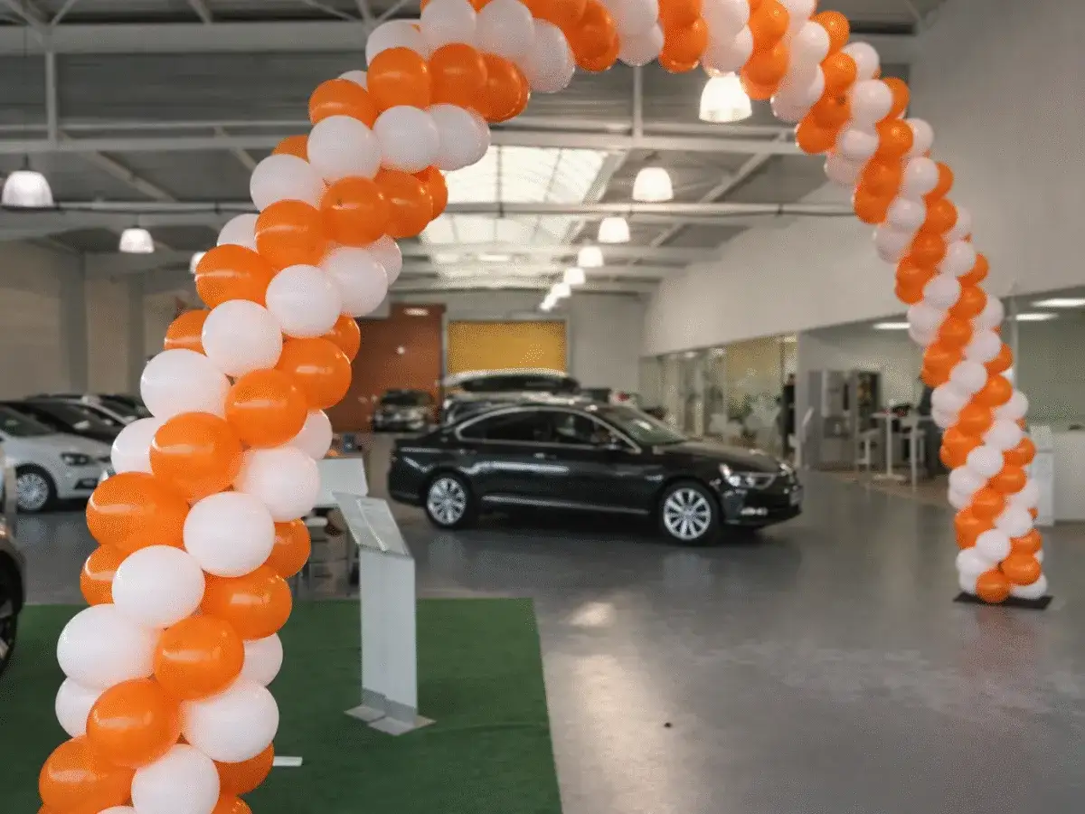 Une arche de ballons orange et blancs pour un &eacute;v&eacute;nement sp&eacute;cial, peut-&ecirc;tre un l&acirc;cher de ballons pour c&eacute;l&eacute;brer l'ouverture d'une concession automobile.