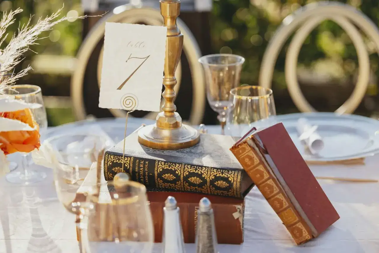 D&eacute;coration de mariage th&egrave;me musique : un chandelier dor&eacute;, des livres anciens et une carte de table 