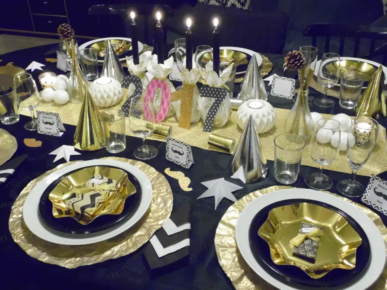 Une élégante deco de table noir et or pour le réveillon, avec des bougies, des chiffres