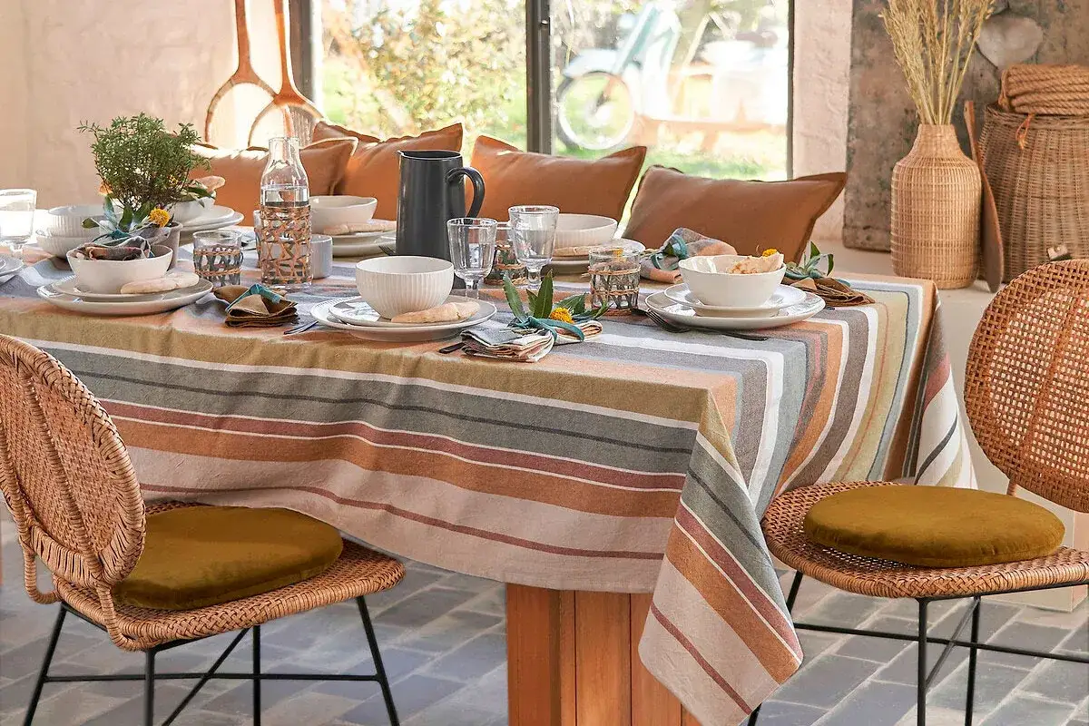 Une table dressée avec une nappe rayée aux tons chauds et naturels. Le choix de cette nappe est parfait pour une ambiance cosy.