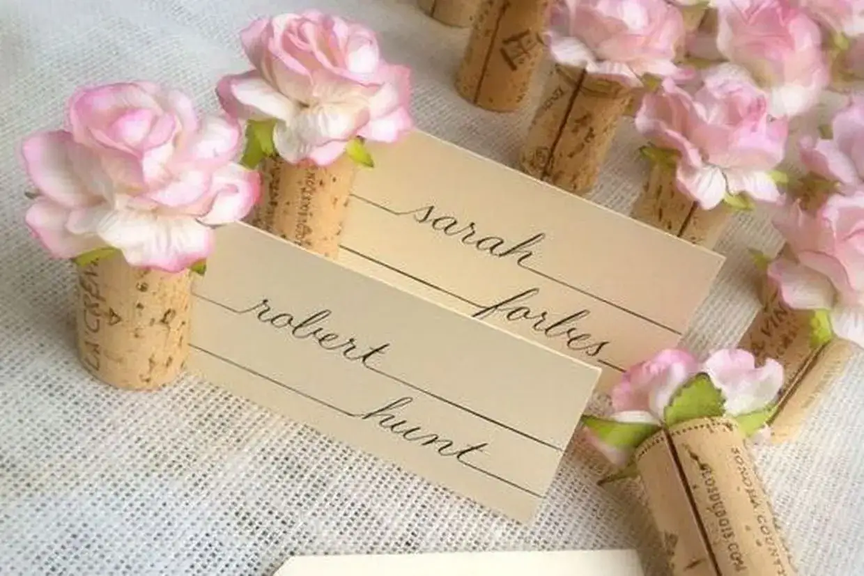Marque-places DIY en bouchons de liège ornés de roses roses. Idéal pour un mariage champêtre.