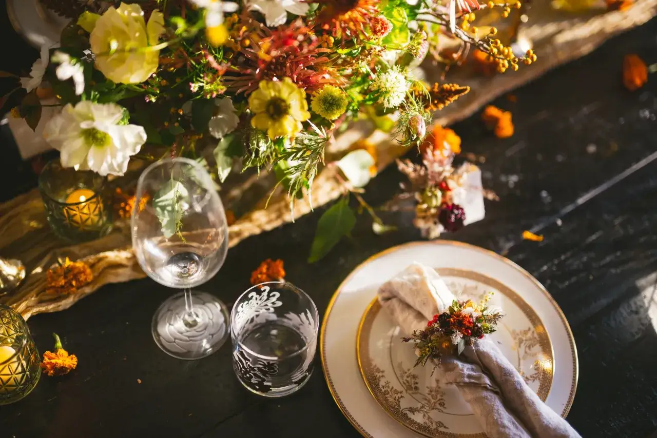Une table dress&eacute;e pour un mariage boh&egrave;me, avec un bouquet champ&ecirc;tre, des bougies et un pliage serviette mariage boh&egrave;me orn&eacute; de fleurs s&eacute;ch&eacute;es.