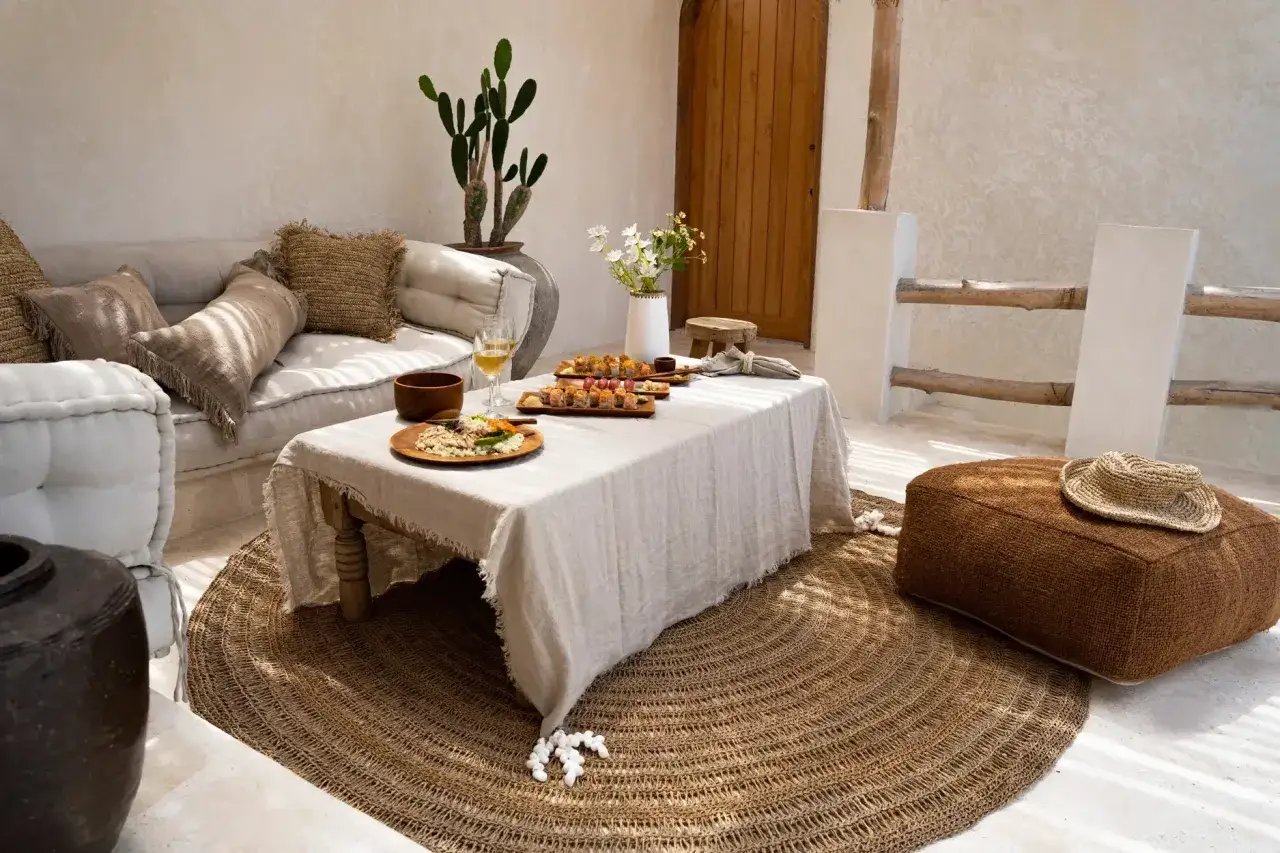Salon extérieur cosy avec canapé, table basse garnie de sushis et tapis rond en toile de jute. Une belle idee deco toile de jute pour une ambiance naturelle.