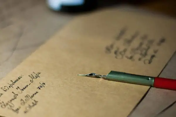 Plume et encre sur papier kraft. On peut écrire famille sur une enveloppe pour envoyer des nouvelles.