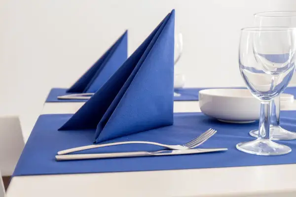 Service de table élégant avec pliage serviette cocktail bleu vif, couverts et verres à pied.