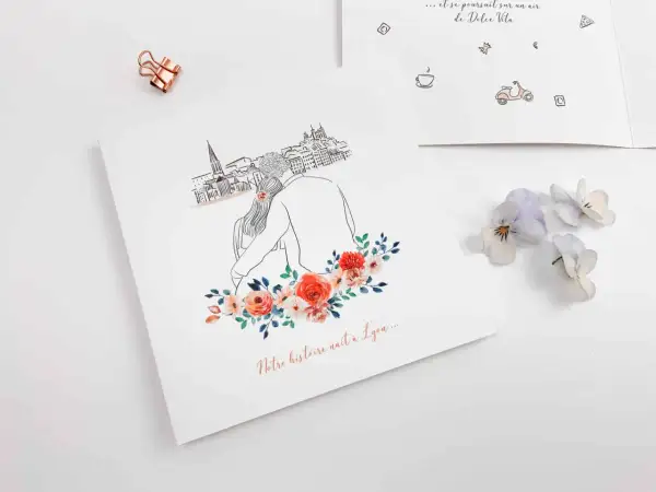Un faire-part avec un dessin de couple devant une ville, orné de fleurs. Le texte "Notre histoire naît à Lyon..." suggère un événement spécial.