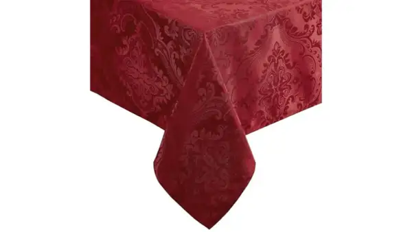 Un coin d'une table recouverte de nappes damassées rouge profond, ornées de motifs floraux complexes.