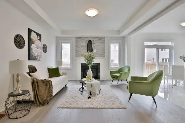 Salon moderne avec canapé blanc, fauteuils verts et une cheminée. La deco de table noir et or ajoute une touche d'élégance.