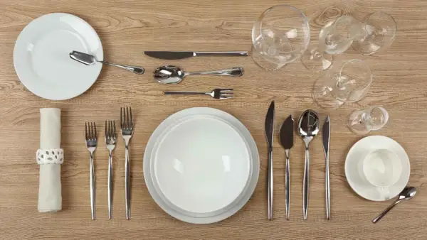 Une **fourchette sur la table** est prête pour le dîner, aux côtés d'assiettes, de verres et d'autres couverts.