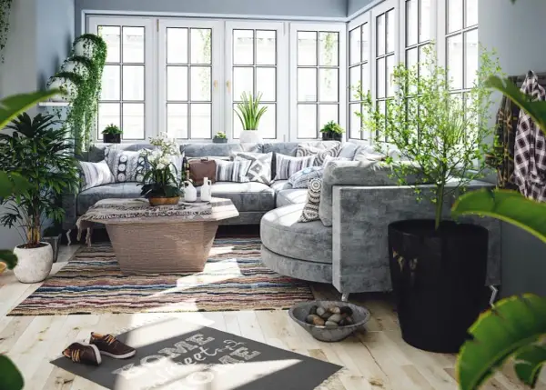 Un salon lumineux et aéré, baigné de lumière naturelle, avec un canapé d'angle confortable, des plantes luxuriantes et une décoration au thème bucolique.